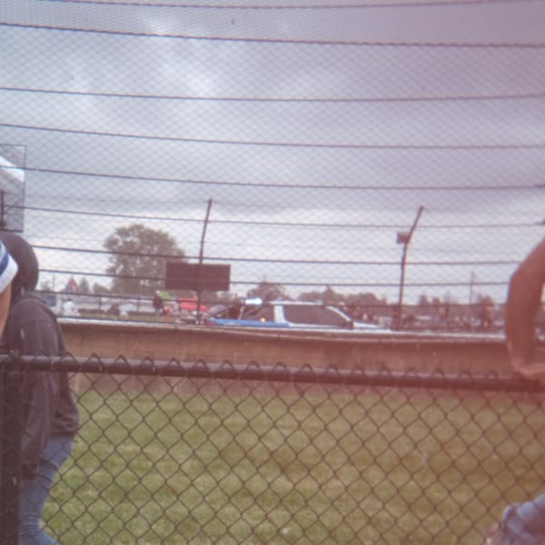 A person standing in front of a fence.