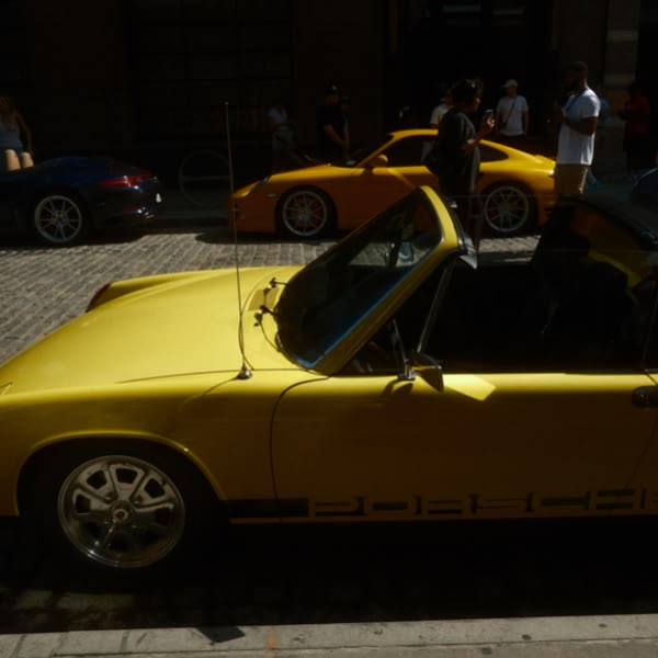 A yellow sports car is parked on a brick road.