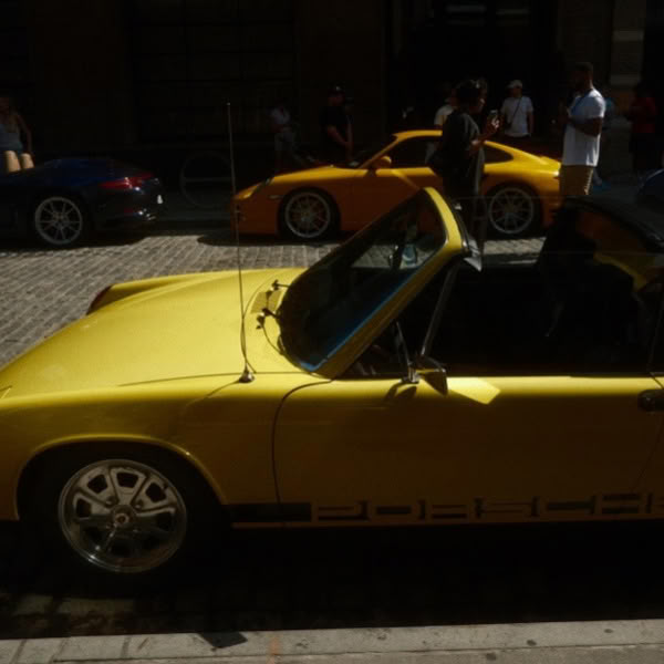 A yellow sports car is parked on a brick road.