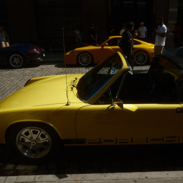 A yellow sports car is parked on a brick road.
