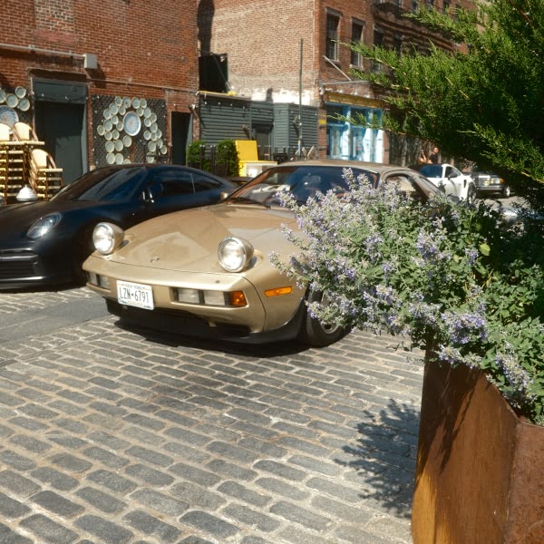A tan sports car parked on a brick road.
