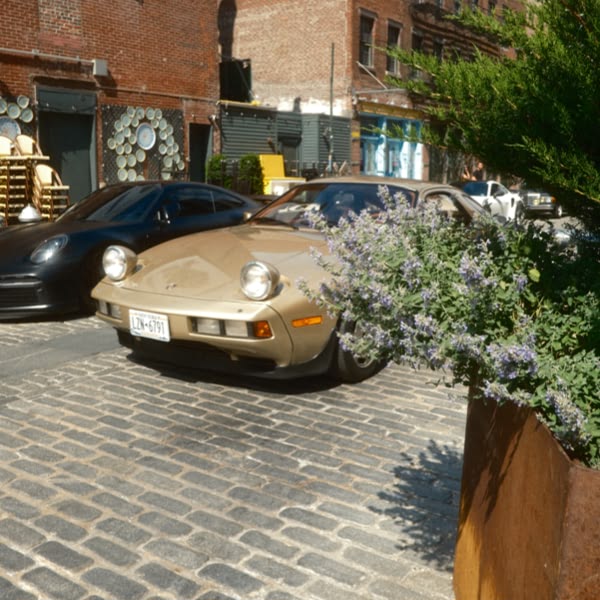 A tan sports car parked on a brick road.