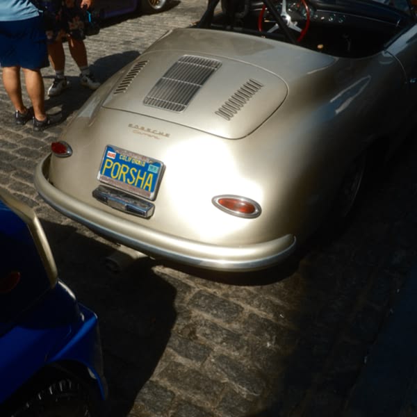 A silver Porsche car with a license plate.