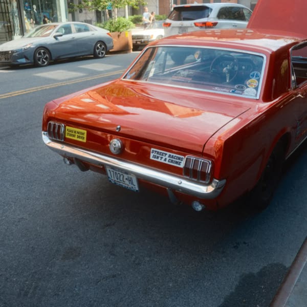 A red car with a yellow sticker on the back.