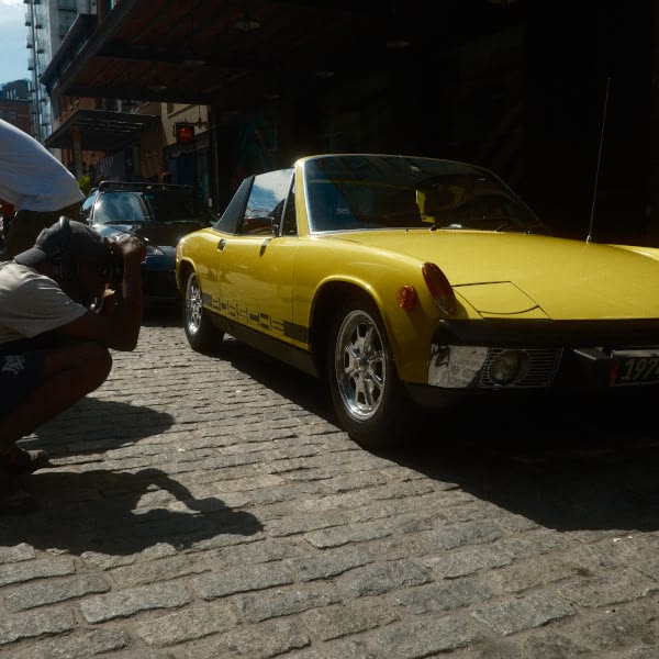 A yellow car is parked on a brick road.