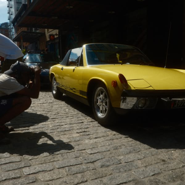 A yellow car is parked on a brick road.