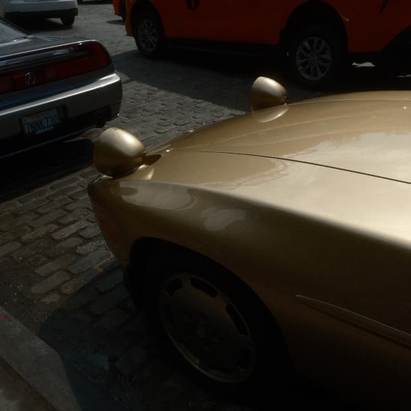 A gold car parked on a brick road.