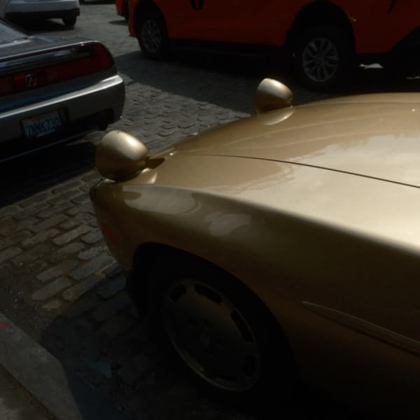 A gold car parked on a brick road.