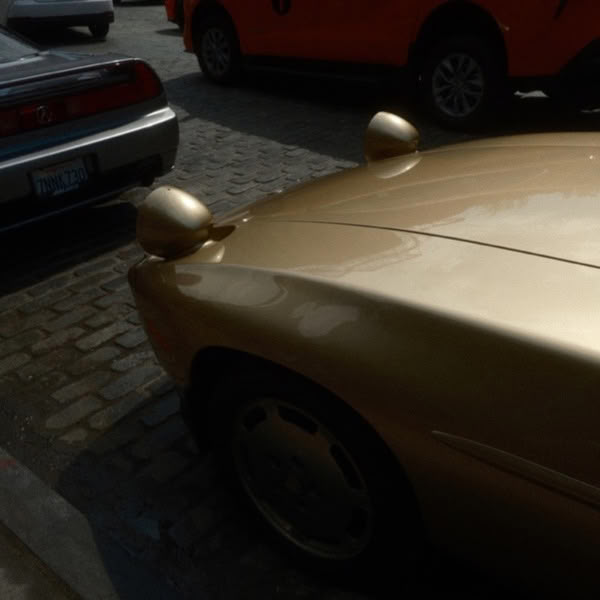 A gold car parked on a brick road.