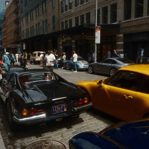 A black sports car is parked on a street next to a yellow sports car.