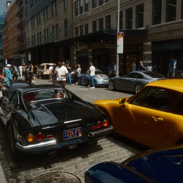 A black sports car is parked on a street next to a yellow sports car.