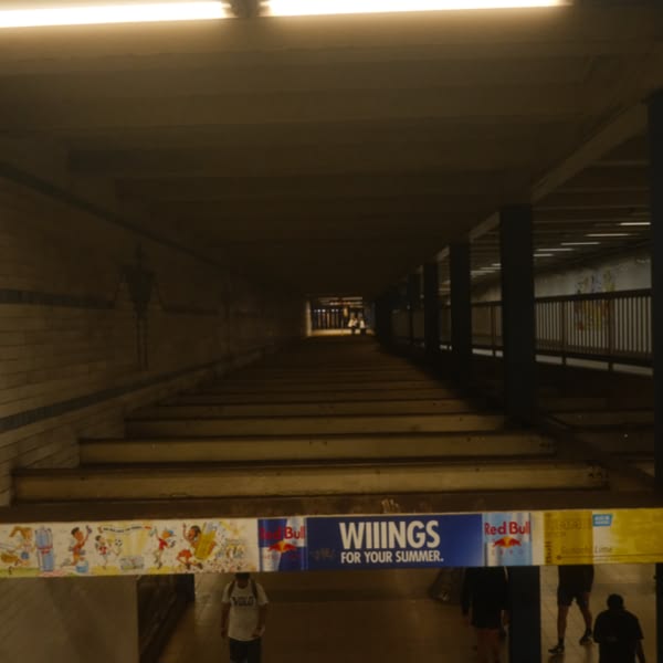 A sign for wings is hanging from the ceiling.