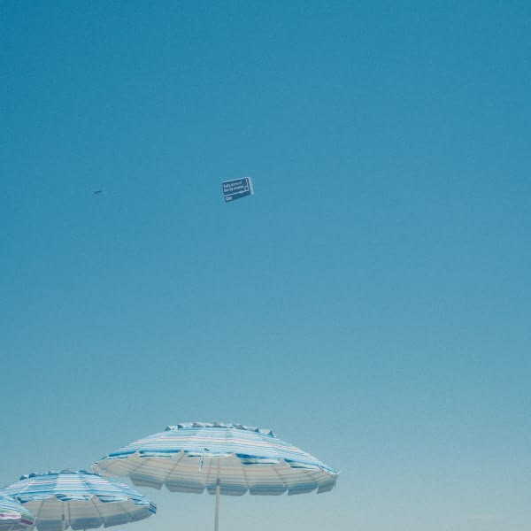 A blue and white umbrella in the sand.